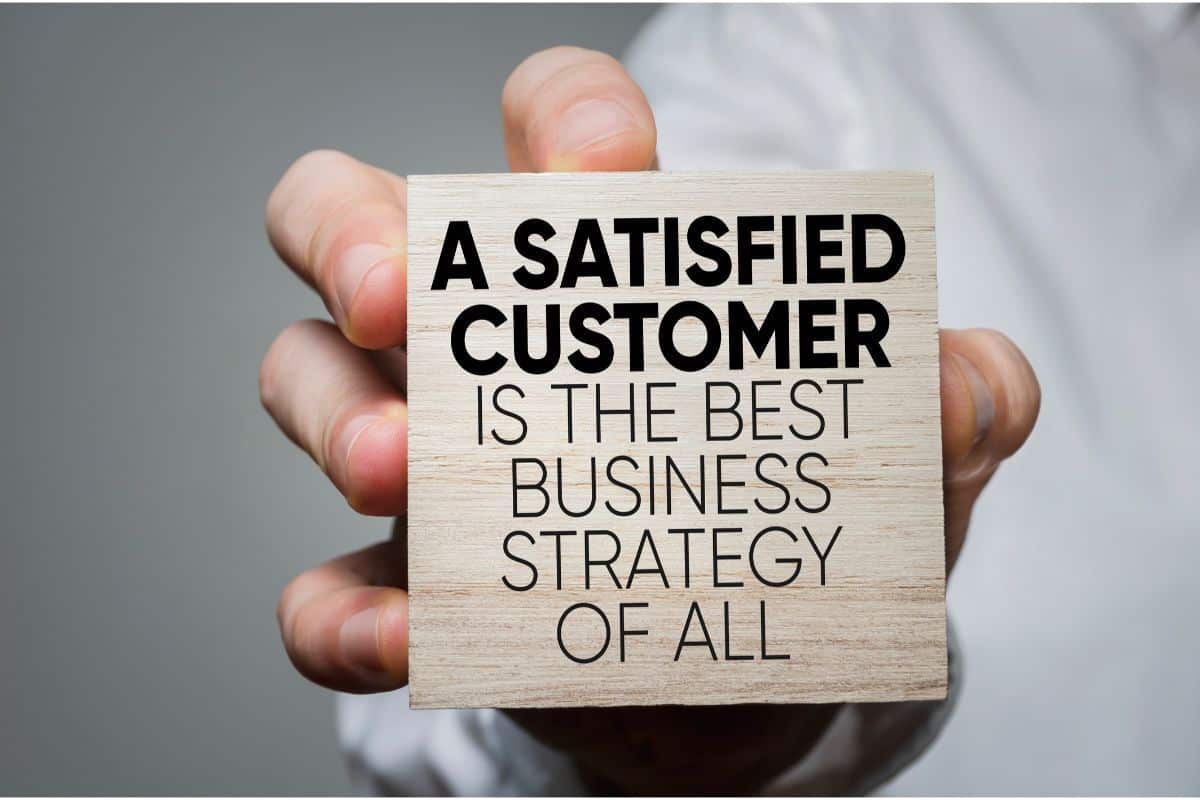 A man holding a sign that says, A satisfied customer is the best business strategy of all
