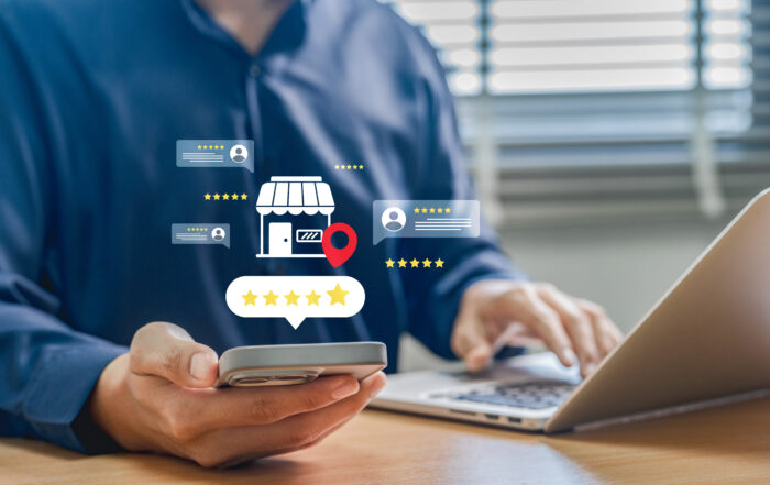 Person using smartphone and laptop to manage online reviews and local business reputation with five-star rating graphics