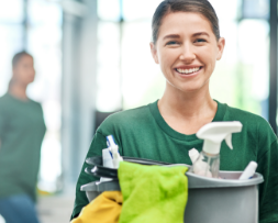 Female cleaner holding bucket and spray bottles, representing digital marketing for cleaning services