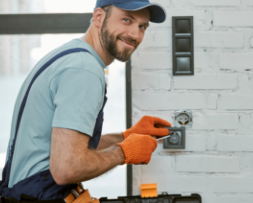 Handyman in gloves repairing an electrical outlet, representing handyman business web design and SEO